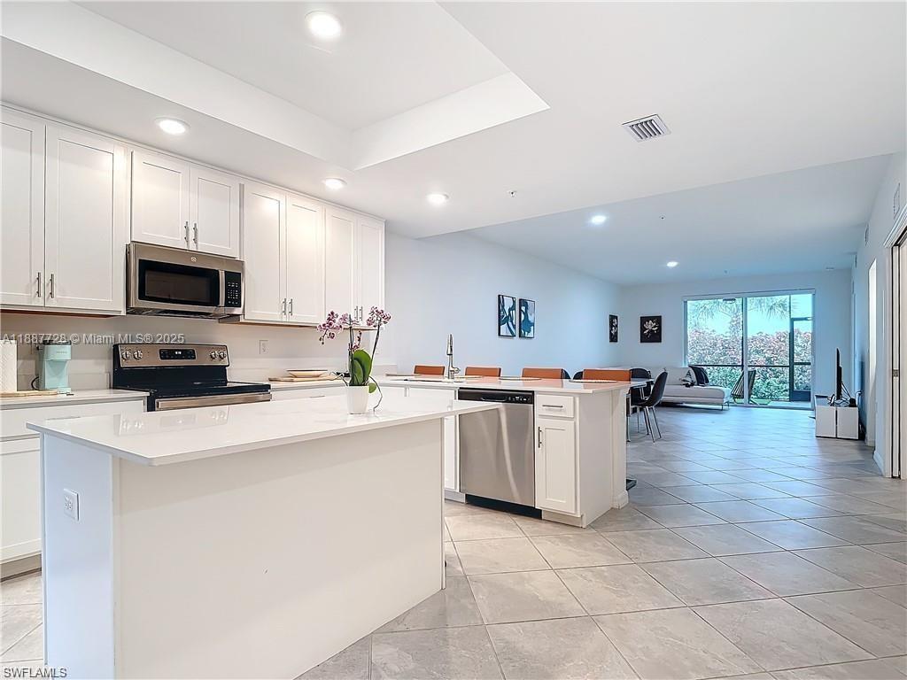 A modern kitchen features white cabinetry, stainless steel appliances, and a large central island — 5453 Double Eagle Cir #3115, Ave Maria FL 34142, AVE MARIA, FL