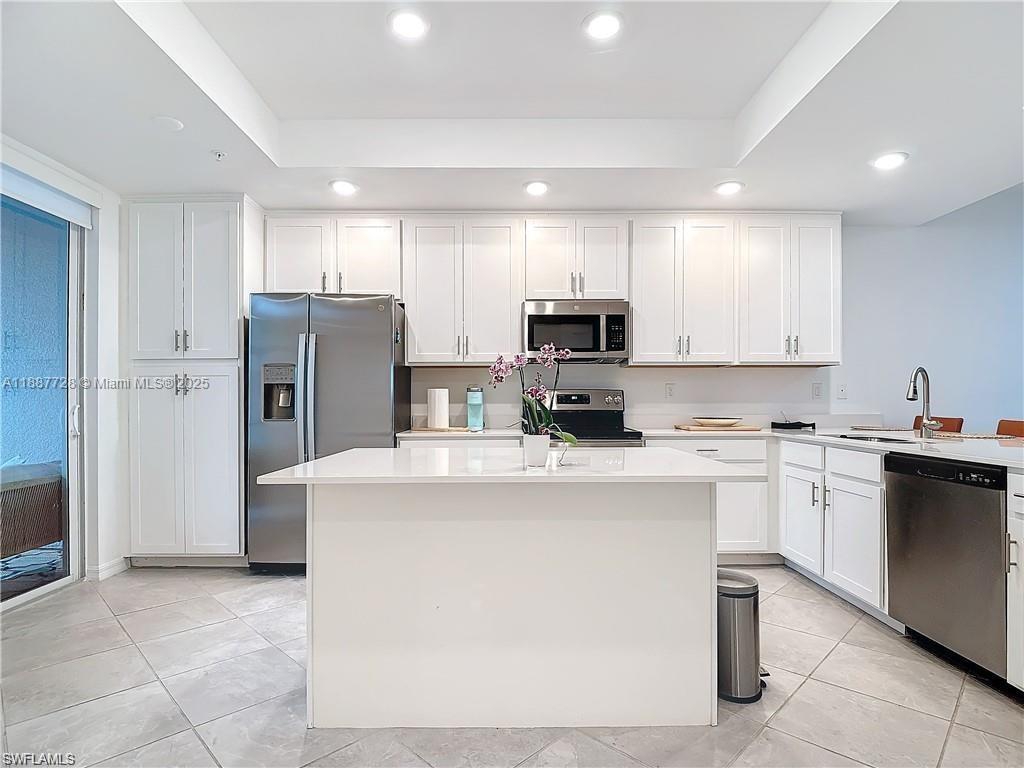A modern kitchen features white cabinetry, stainless steel appliances, a central island, and tile flooring — 5453 Double Eagle Cir #3115, Ave Maria FL 34142, AVE MARIA, FL