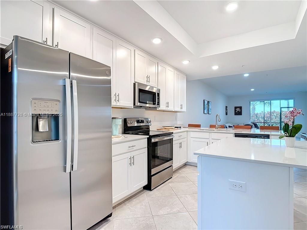 A modern kitchen features white cabinetry, stainless steel appliances, and a central island — 5453 Double Eagle Cir #3115, Ave Maria FL 34142, AVE MARIA, FL