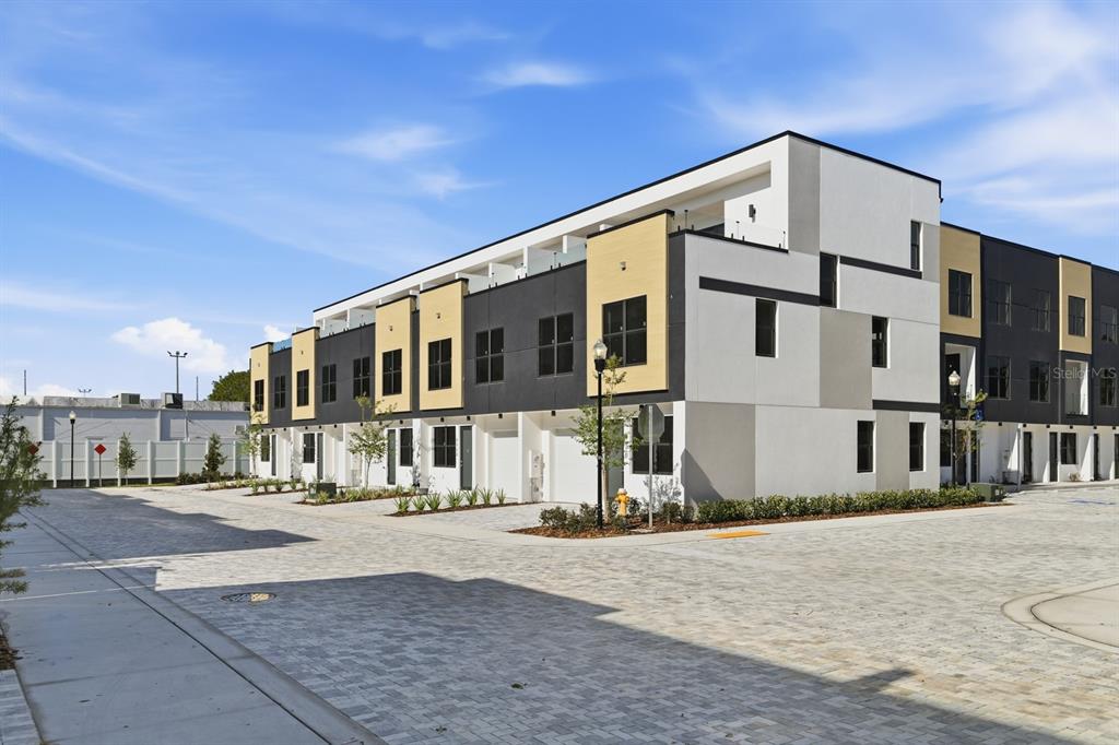 A modern multi-story townhouse complex features a paved driveway and a mix of exterior finishes — 8401 MODANO PLACE, TAMPA, FL