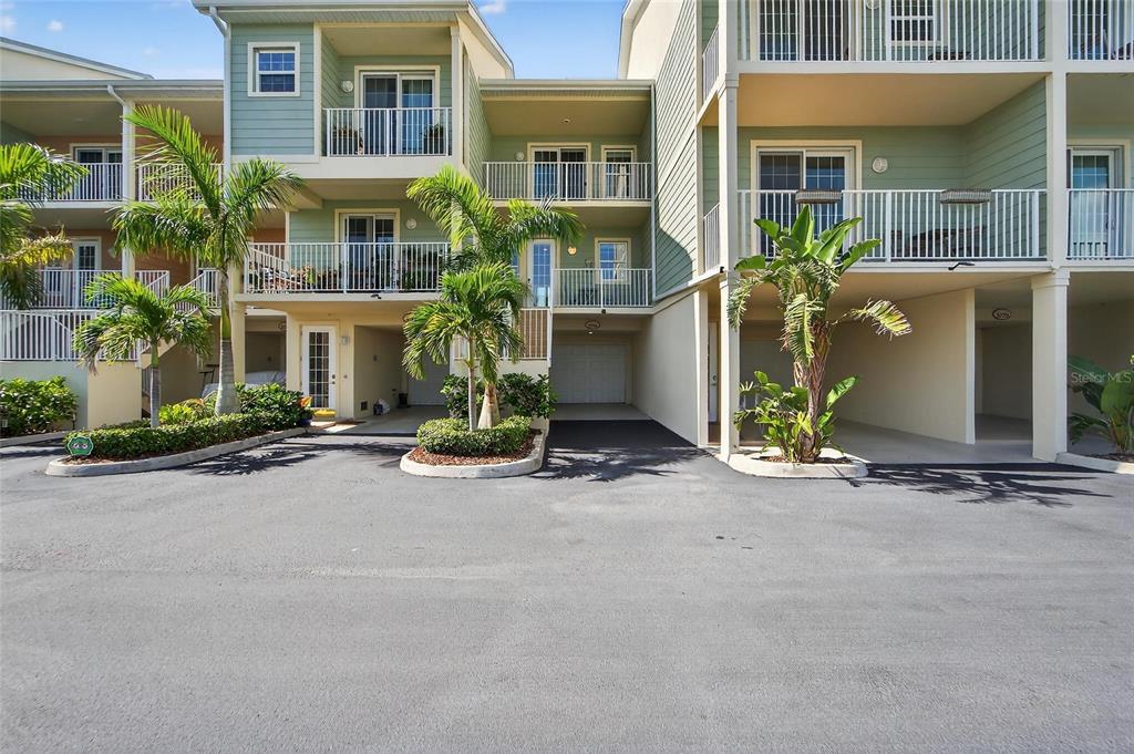 The exterior of a multi-story residential building features balconies, palm trees, and covered parking — 3266 MANGROVE POINT DRIVE, RUSKIN, FL