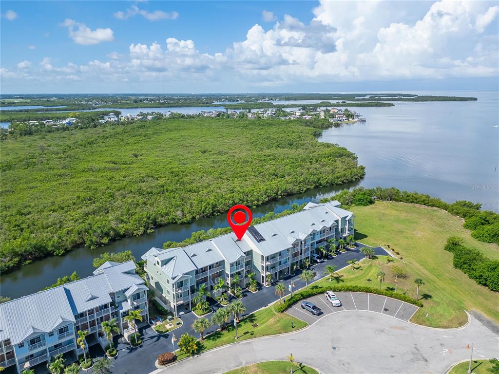 An aerial view shows a multi-story residential building situated near a waterway and mangroves — 3266 MANGROVE POINT DRIVE, RUSKIN, FL