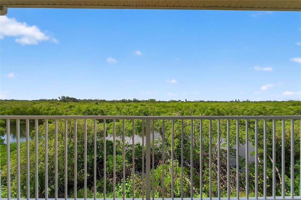 A balcony overlooks a dense green forest and a narrow waterway under a blue sky — 3266 MANGROVE POINT DRIVE, RUSKIN, FL
