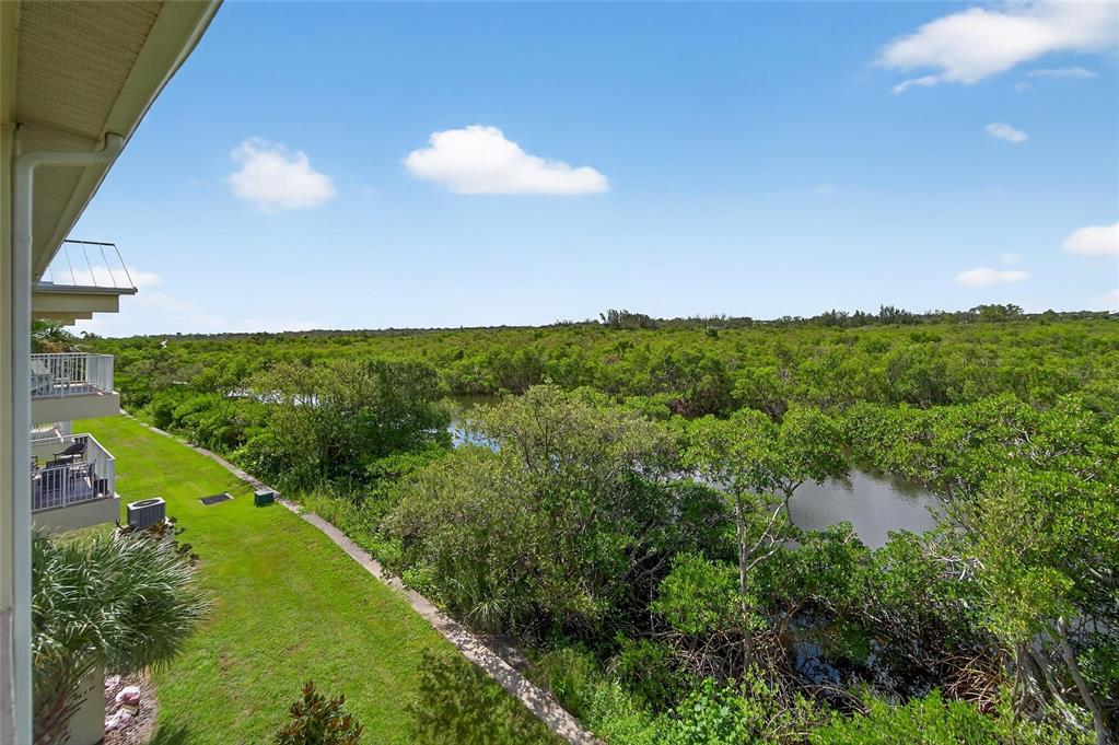 An elevated view from a balcony overlooking a grassy lawn, mangroves, and a small waterway — 3266 MANGROVE POINT DRIVE, RUSKIN, FL