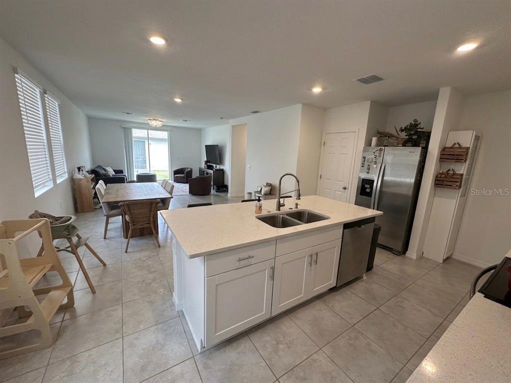A kitchen with a white island and stainless steel appliances overlooks an open dining area — 3864 GIORGIO DRIVE, WINTER HAVEN, FL