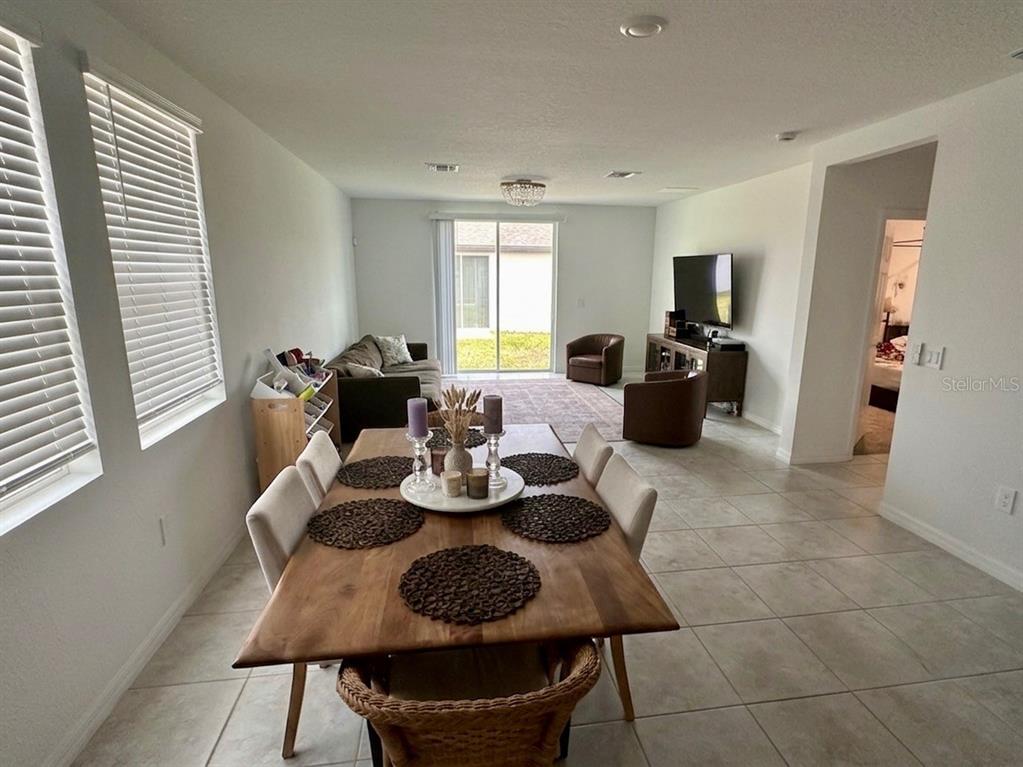 A dining area with a wooden table leads into an open-concept living room with tile floors — 3864 GIORGIO DRIVE, WINTER HAVEN, FL