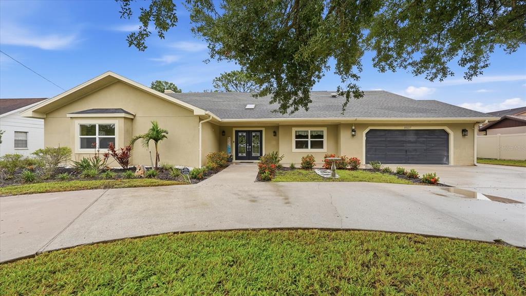 A single-story house with a beige exterior, a dark garage door, and a concrete driveway — 15127 PENNINGTON ROAD, TAMPA, FL