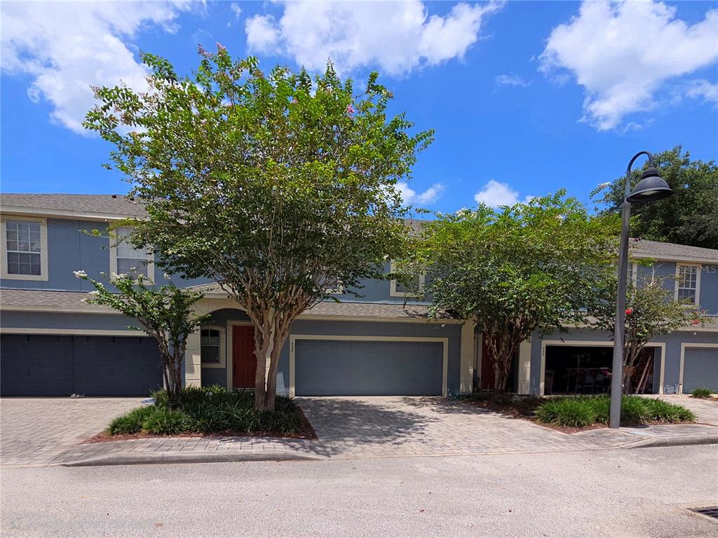 A two-story blue townhouse with a paved driveway, two garage doors, and two trees — 337 CORAL BEACH CIRCLE, CASSELBERRY, FL
