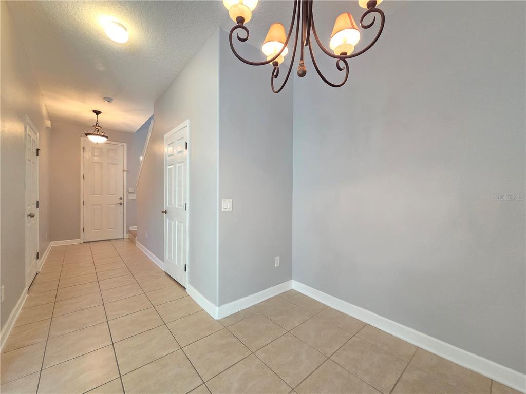 An entryway with tile flooring, a chandelier, and white doors leads to a front door — 337 CORAL BEACH CIRCLE, CASSELBERRY, FL