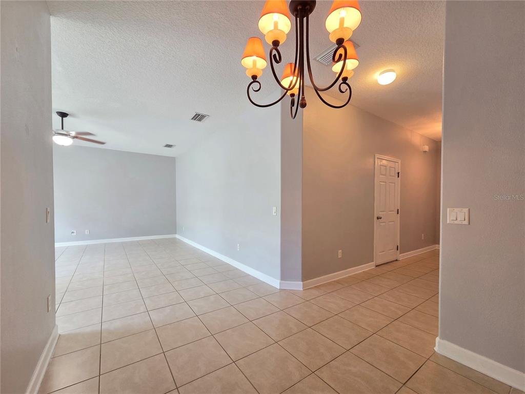 An interior view shows a tiled entryway leading to a living area with a chandelier — 337 CORAL BEACH CIRCLE, CASSELBERRY, FL