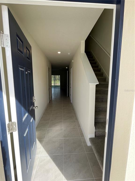 An entryway features a tiled floor, a blue front door, and carpeted stairs leading upward — 3057 CANARY AVENUE, DAVENPORT, FL