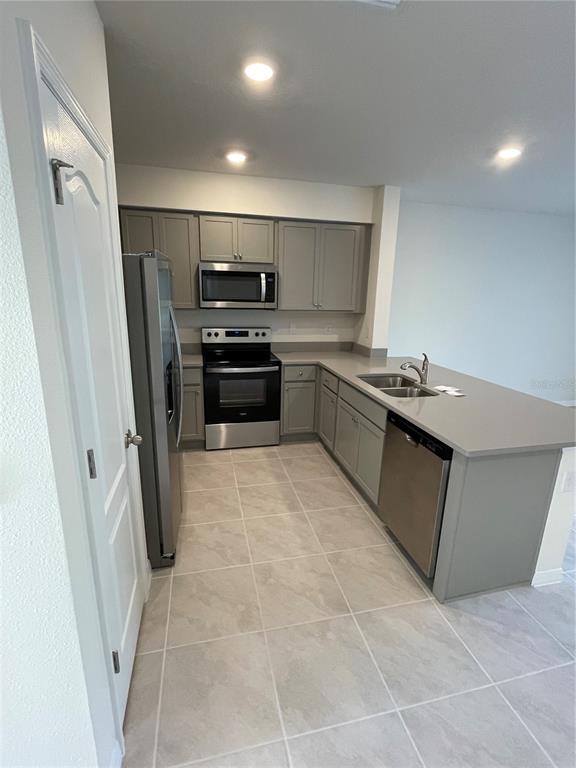 A kitchen features gray cabinets, stainless steel appliances, and a large island with a sink — 3057 CANARY AVENUE, DAVENPORT, FL