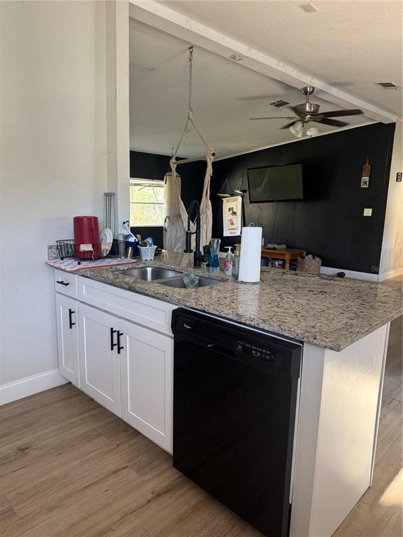 A kitchen island with a granite countertop, white cabinets, and a black dishwasher — 8602 TREASURE ISLAND ROAD, LEESBURG, FL