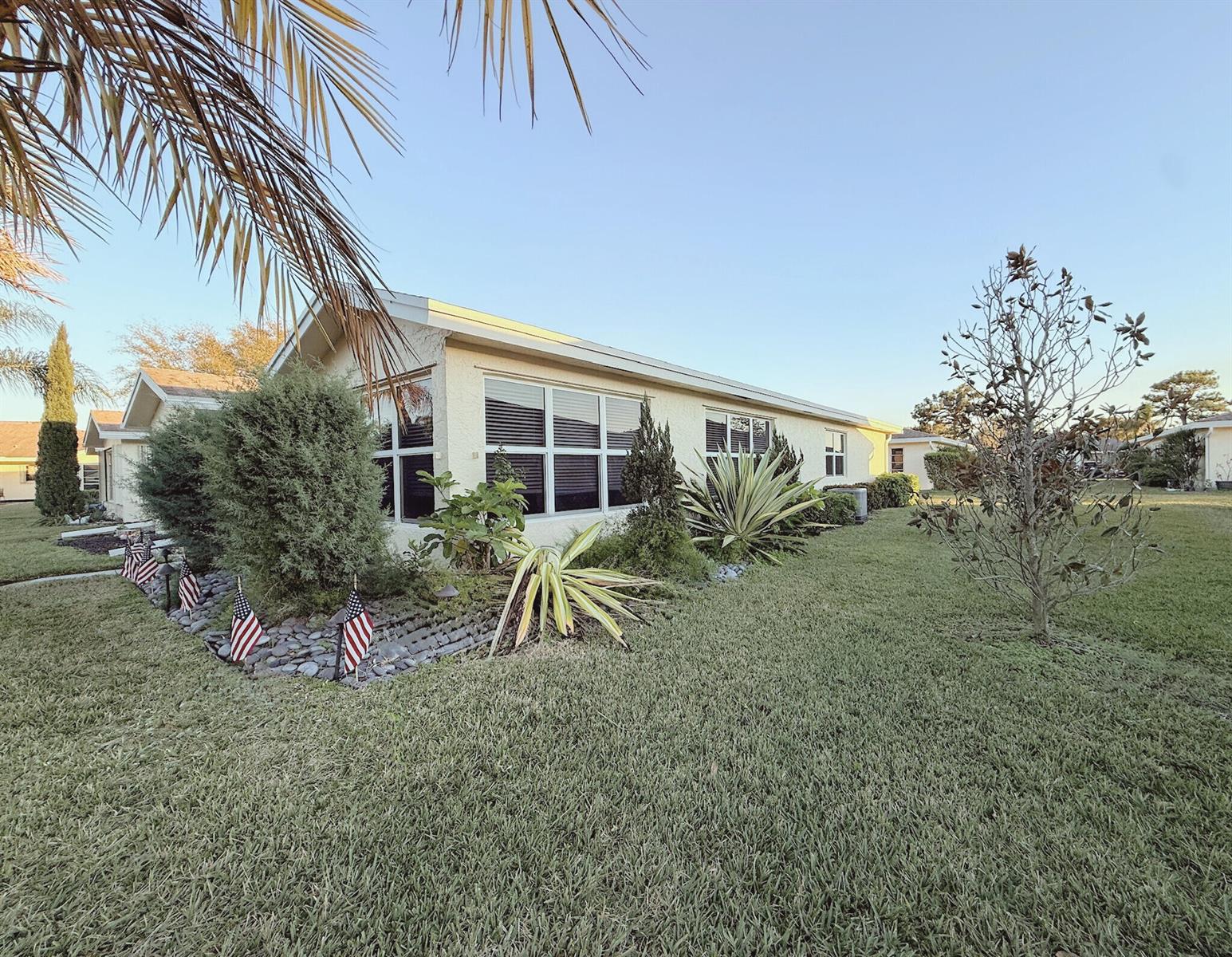 A single-story house with a light-colored exterior, large windows, and a landscaped front yard — 5301 Lakefront Boulevard # D, Delray Beach FL 33484, DELRAY BEACH, FL