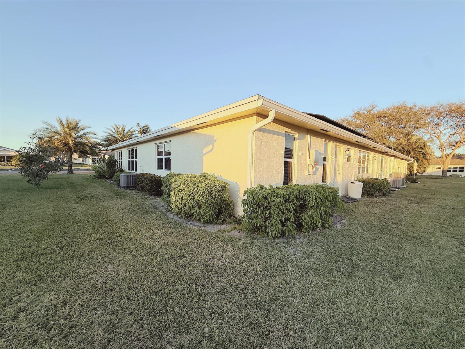 A side view of a single-story stucco building with a lawn and landscaping — 5301 Lakefront Boulevard # D, Delray Beach FL 33484, DELRAY BEACH, FL
