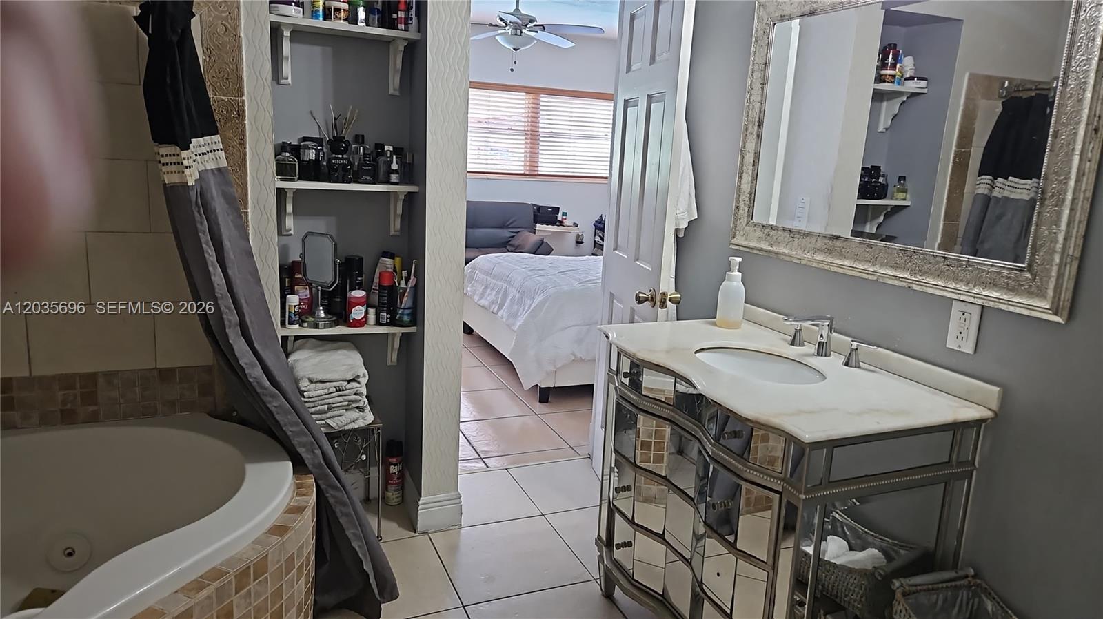 A bathroom features a mirrored vanity, a soaking tub, and open shelving leading to a bedroom — 6895 Tamiami Canal Rd, Miami FL 33126, MIAMI, FL