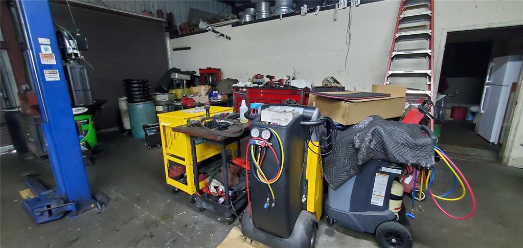 A cluttered automotive repair shop features a vehicle lift, tool carts, and diagnostic equipment — 2714 ORLANDO, SANFORD, FL