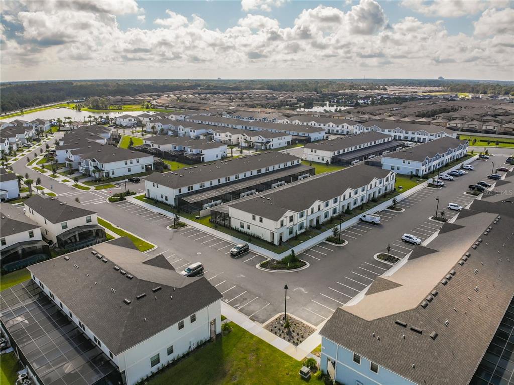 An aerial view shows multiple rows of white townhomes with dark roofs and parking lots — 2430 TANGIER DRIVE, KISSIMMEE, FL