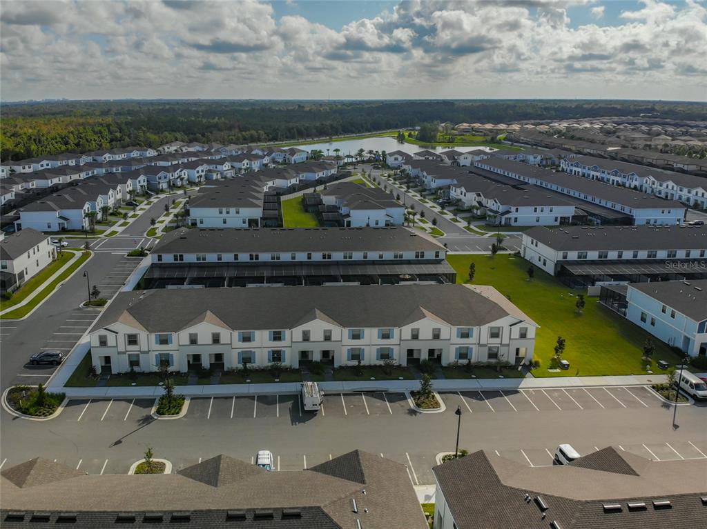 An aerial view shows rows of modern townhouses with dark roofs and parking lots — 2430 TANGIER DRIVE, KISSIMMEE, FL