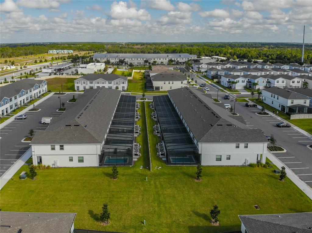 An aerial view shows two rows of townhomes with screened-in pools and adjacent parking lots — 2430 TANGIER DRIVE, KISSIMMEE, FL