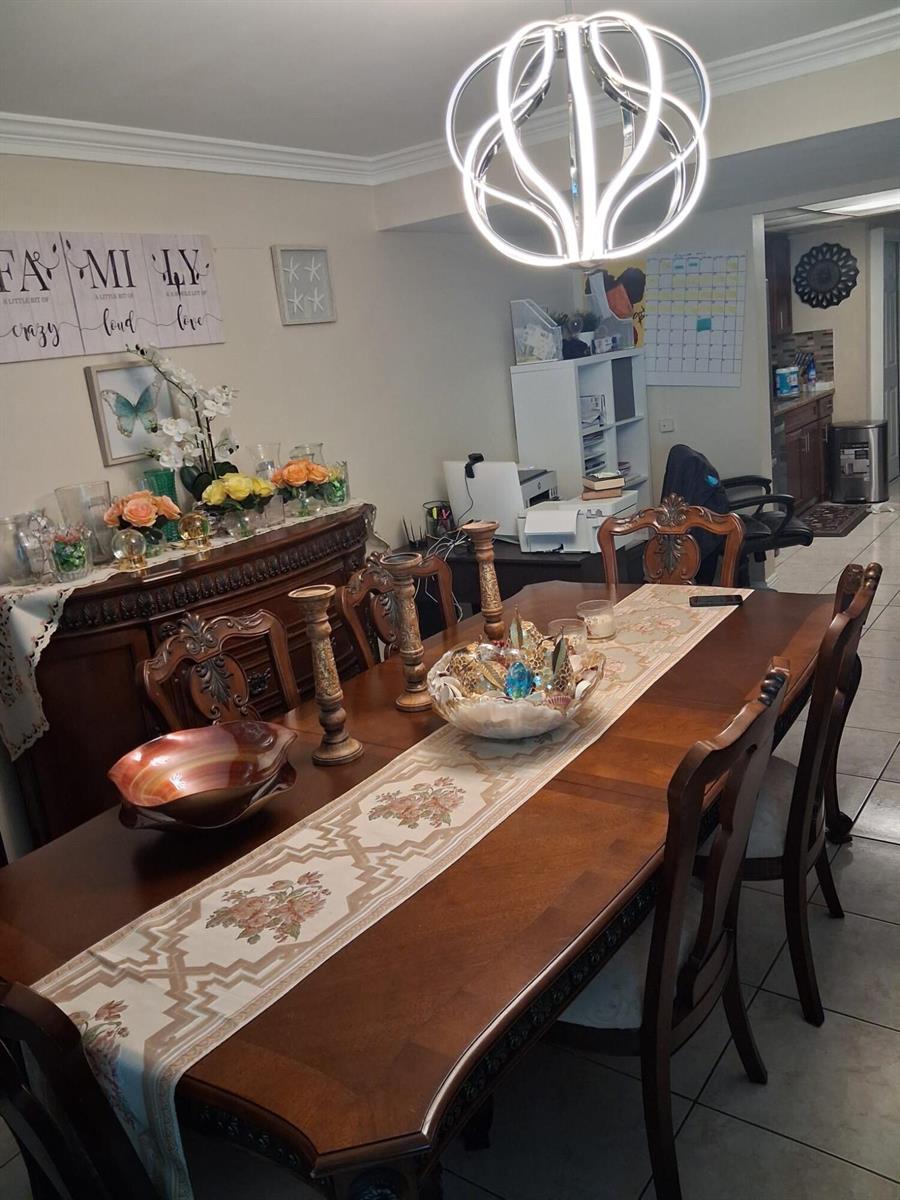 A dining room features a wooden table, chairs, a sideboard, and a modern circular chandelier — 9752 NW 37th Street # 7g, Sunrise FL 33351, SUNRISE, FL