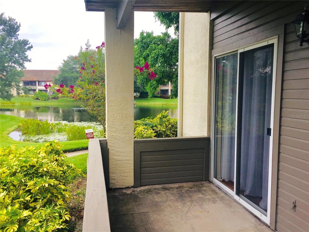 A covered patio with a concrete floor overlooks a pond and surrounding apartment buildings — 10263 GANDY BOULEVARD N UNIT 513, ST PETERSBURG, FL