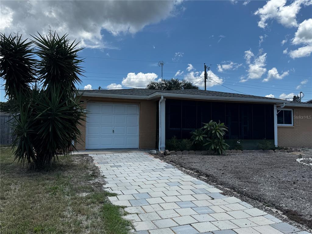 A single-story house with a brick exterior, a white garage door, and a paved walkway — 2552 LIMEWOOD DRIVE, HOLIDAY, FL