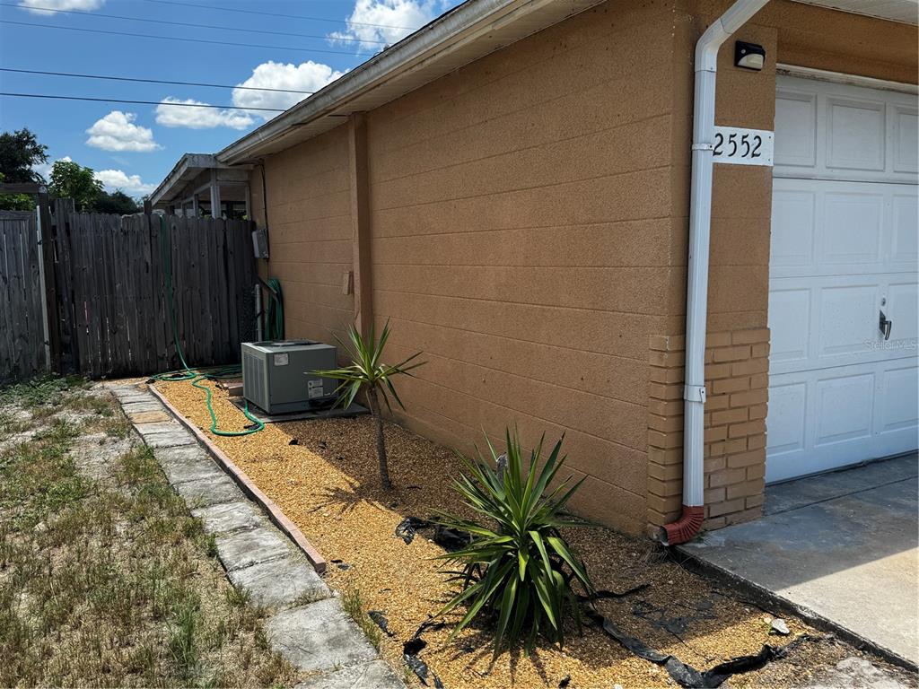 A side view of a tan stucco house exterior with a garage and landscaping — 2552 LIMEWOOD DRIVE, HOLIDAY, FL