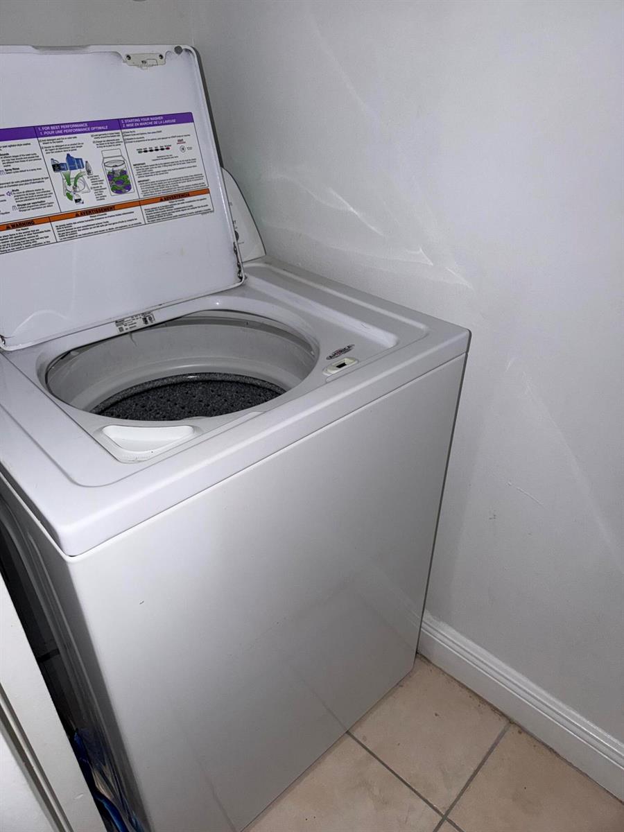 A white top-loading washing machine sits in a corner against a white wall — 1285 SW 46th Avenue # 2709, Pompano Beach FL 33069, POMPANO BEACH, FL