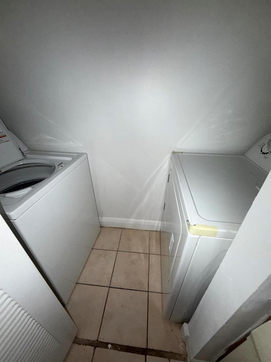 A laundry closet features a white top-loading washer and dryer on a tiled floor — 1285 SW 46th Avenue # 2709, Pompano Beach FL 33069, POMPANO BEACH, FL