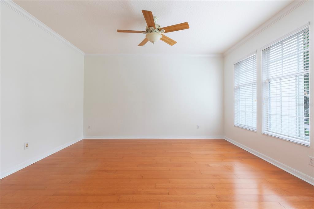 An empty room with hardwood floors, white walls, a ceiling fan, and large windows — 1003 JUEL STREET, ORLANDO, FL