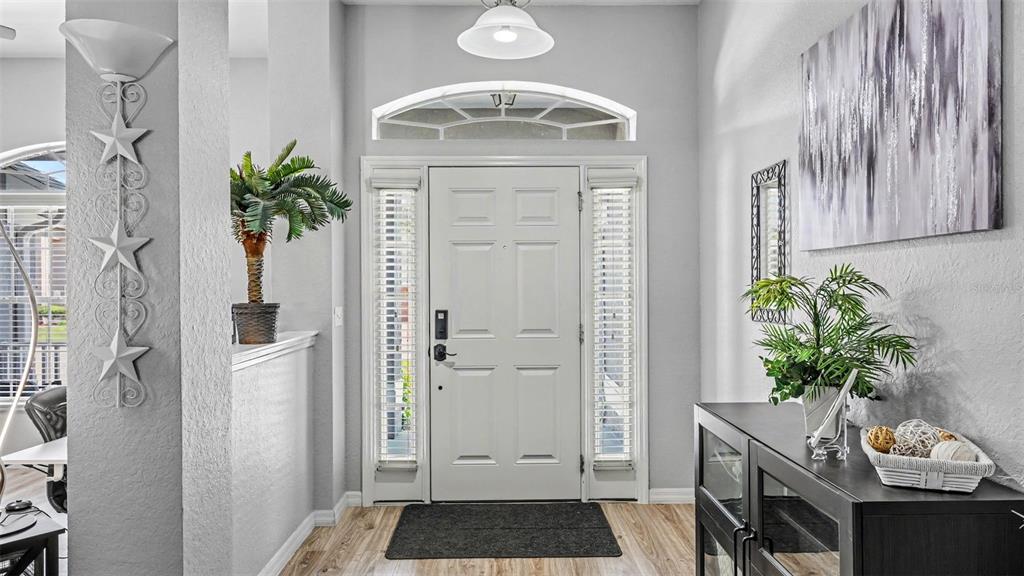 A living room features gray walls, wood-look flooring, a vaulted ceiling, and brown furniture — 2855 BLACKWATER OAKS DRIVE, MULBERRY, FL