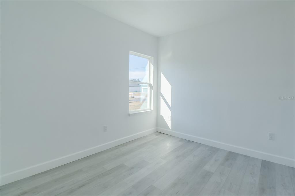 An empty bedroom features white walls, light-colored wood-look flooring, and a single window — 3110 SW 127TH LANE ROAD, OCALA, FL
