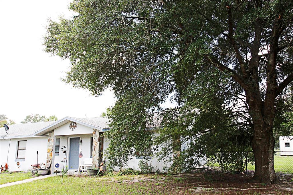 A single-story house with a stone-accented entryway sits beneath a large, sprawling oak tree — 7615 N LAZY TRAIL, CRYSTAL RIVER, FL