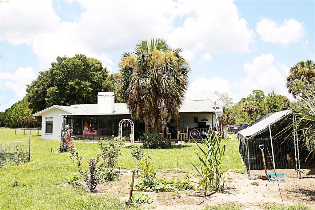 A single-story house with a large palm tree, a screened porch, and a chicken coop — 7615 N LAZY TRAIL, CRYSTAL RIVER, FL