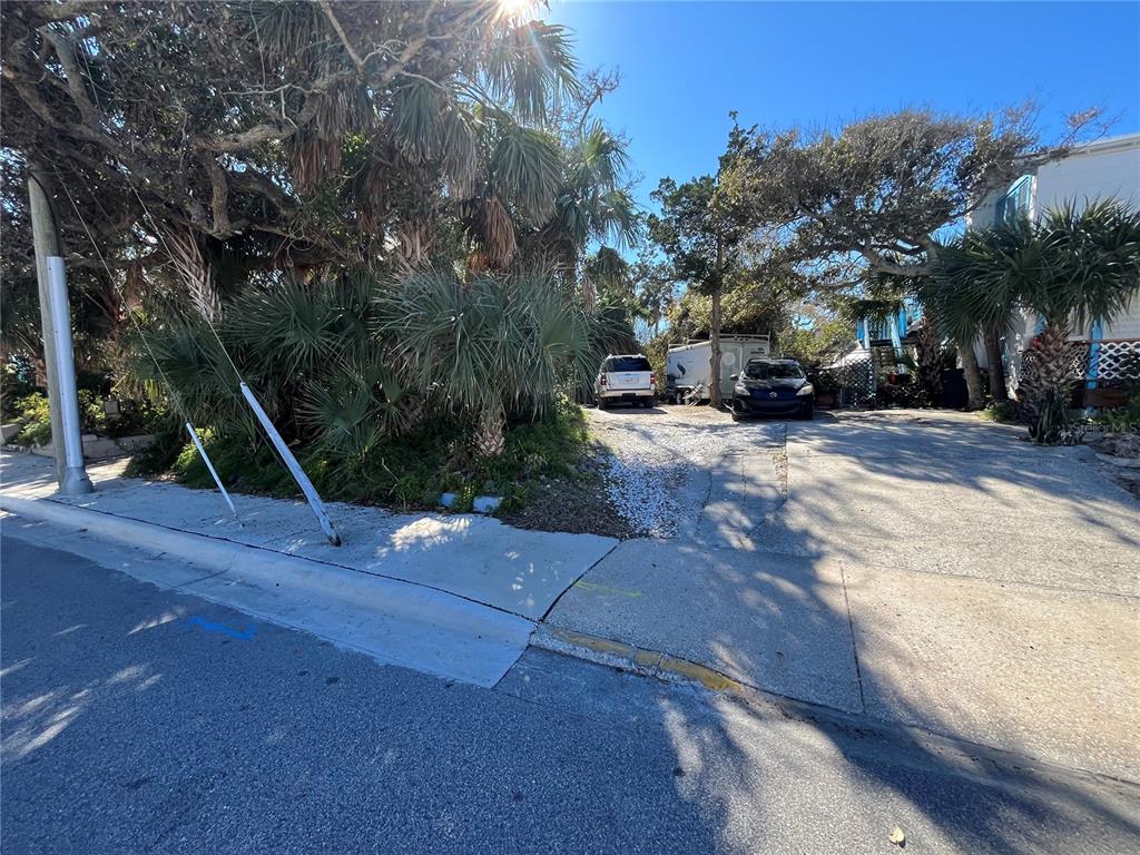 A paved driveway leads to a gravel parking area shaded by trees and palm trees — N HOLLYWOOD AVENUE, DAYTONA BEACH, FL