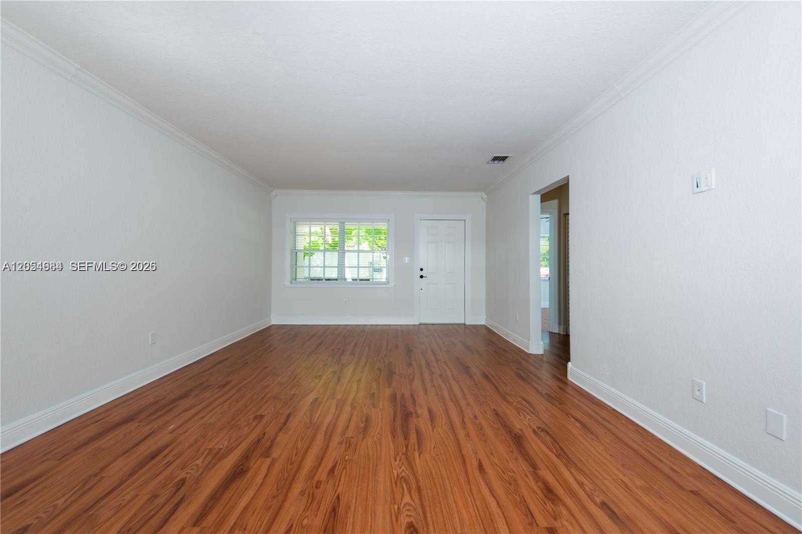 An empty room features white walls, crown molding, and wood-look flooring with a windowed door — 5490 SW 57 Ave # 0, Miami FL 33155, MIAMI, FL