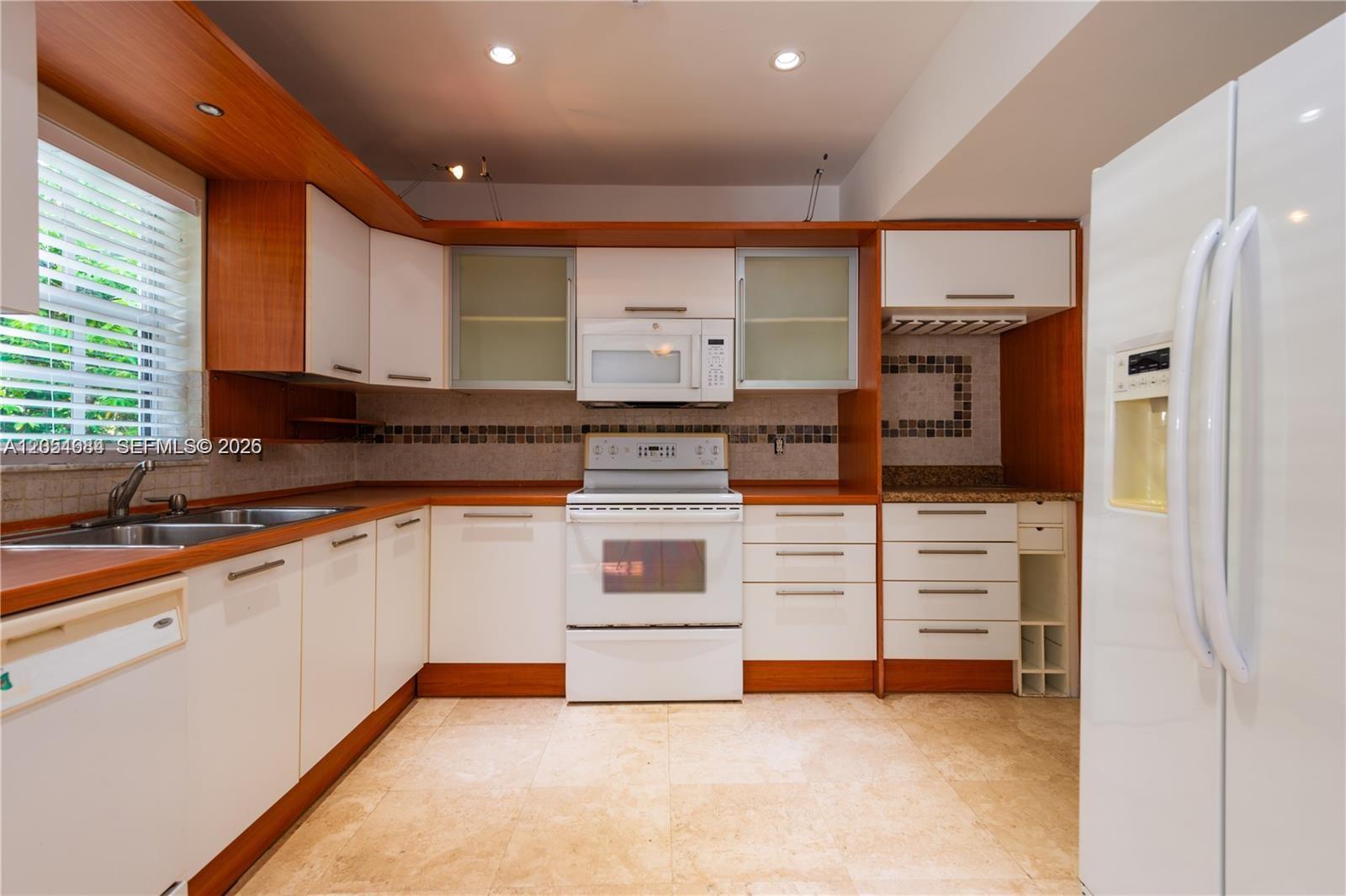 A kitchen features white cabinets, wood trim, a white stove, and a white refrigerator — 5490 SW 57 Ave # 0, Miami FL 33155, MIAMI, FL