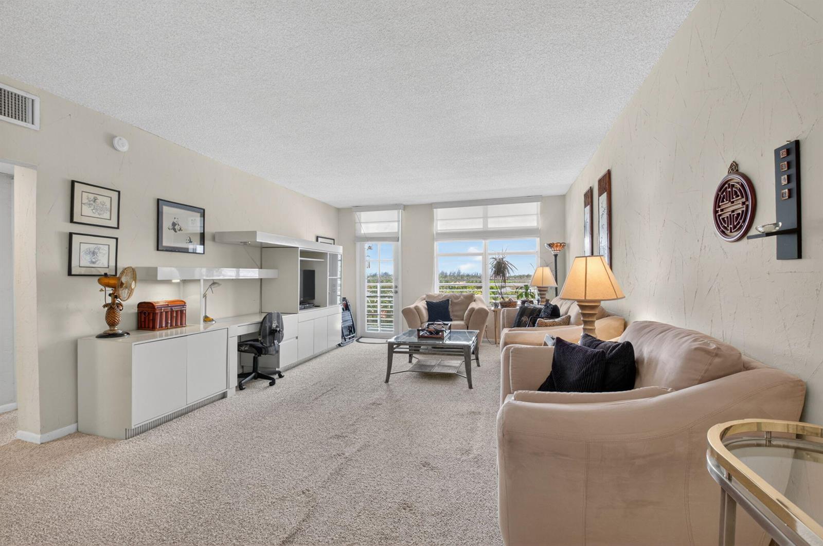 A living room features beige carpet, neutral walls, a built-in desk unit, and two sofas — 2851 S Ocean Boulevard # 5m, Boca Raton FL 33432, BOCA RATON, FL