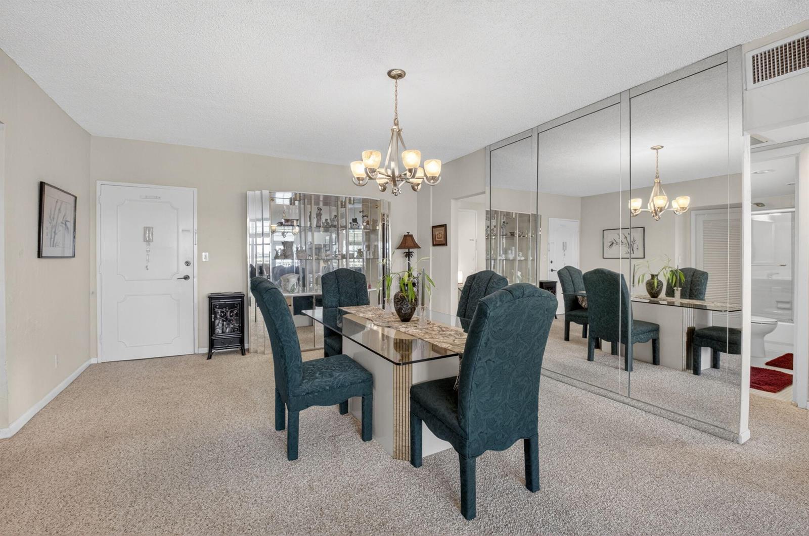 A dining room with a glass table, dark chairs, a chandelier, and mirrored wall panels — 2851 S Ocean Boulevard # 5m, Boca Raton FL 33432, BOCA RATON, FL