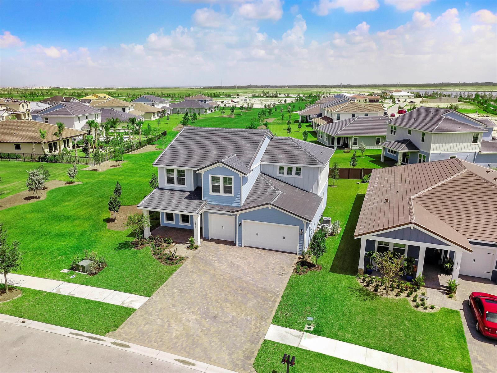 An aerial view shows a two-story blue house with a paved driveway and tiled roof — 19551 Split Rail Run, Loxahatchee FL 33470, LOXAHATCHEE, FL