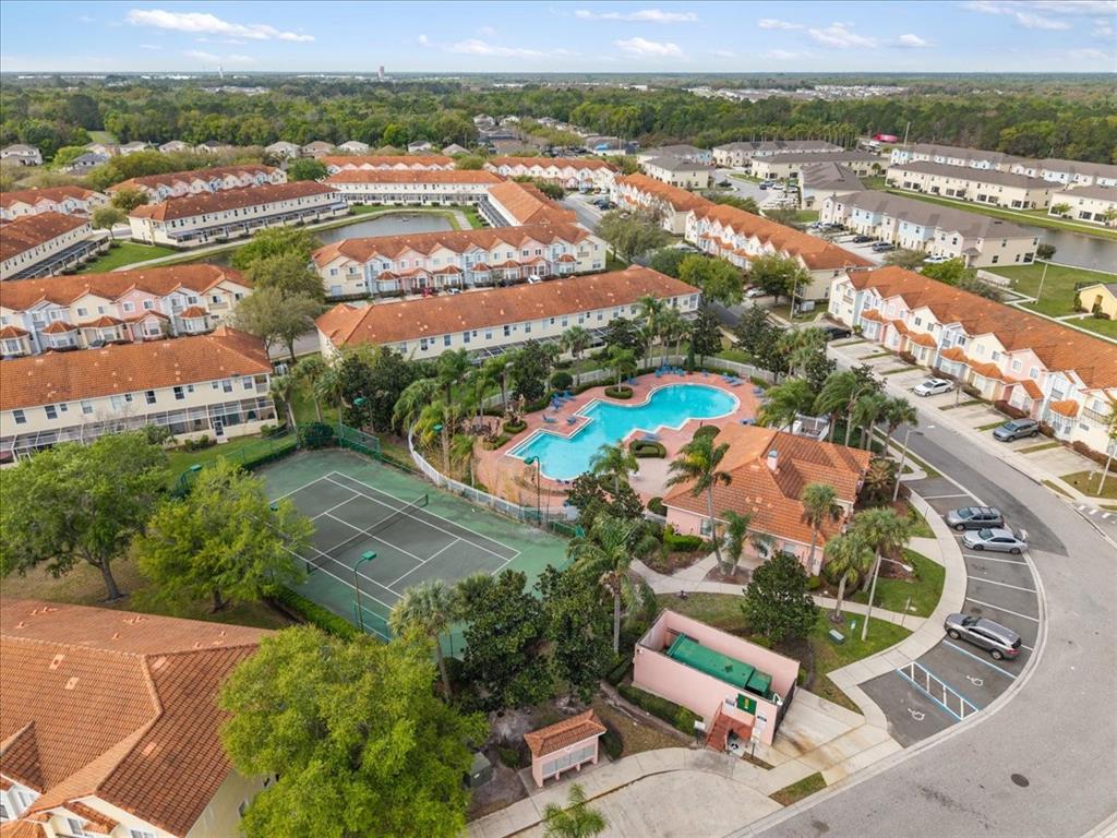 An aerial view shows a residential complex with a swimming pool, tennis court, and parking — 4855 CORAL CASTLE DRIVE, KISSIMMEE, FL