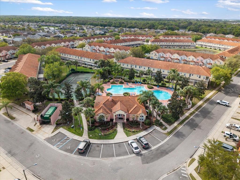 An aerial view shows a community clubhouse with a swimming pool and tennis court — 4855 CORAL CASTLE DRIVE, KISSIMMEE, FL