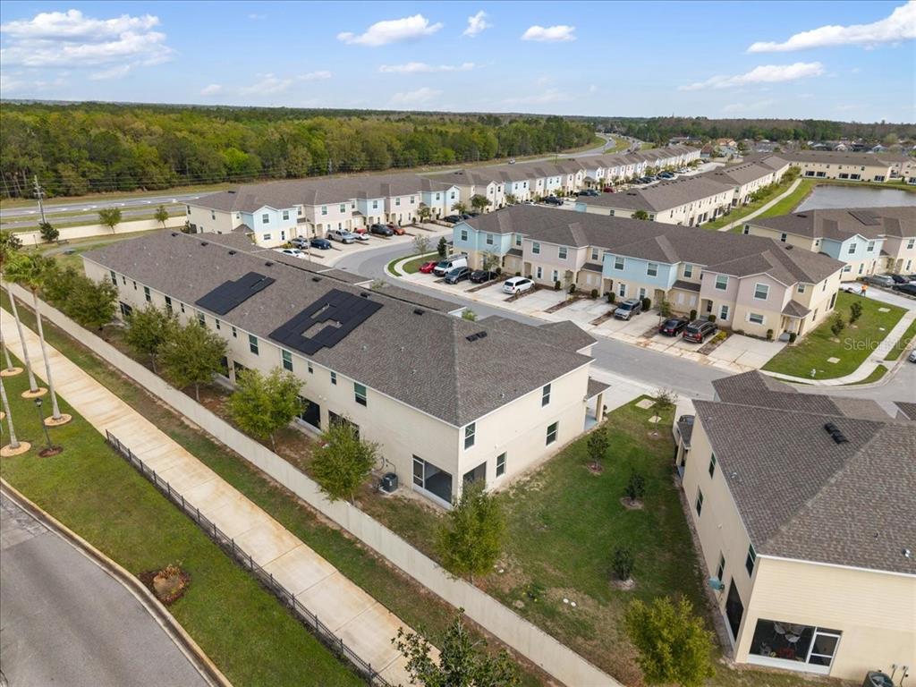 An aerial view shows multiple multi-story townhomes with driveways, a sidewalk, and a fenced yard — 4855 CORAL CASTLE DRIVE, KISSIMMEE, FL