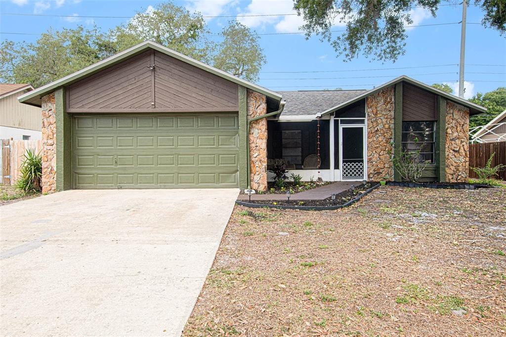 A single-story house with a two-car garage, stone facade, and a screened front entryway — 4105 SPRING WAY CIRCLE, VALRICO, FL