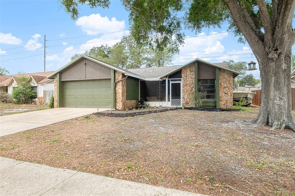 A single-story house with a stone facade, green trim, and a two-car garage — 4105 SPRING WAY CIRCLE, VALRICO, FL