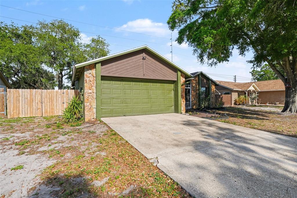 A single-story house with a green garage door, stone accents, and a concrete driveway — 4105 SPRING WAY CIRCLE, VALRICO, FL