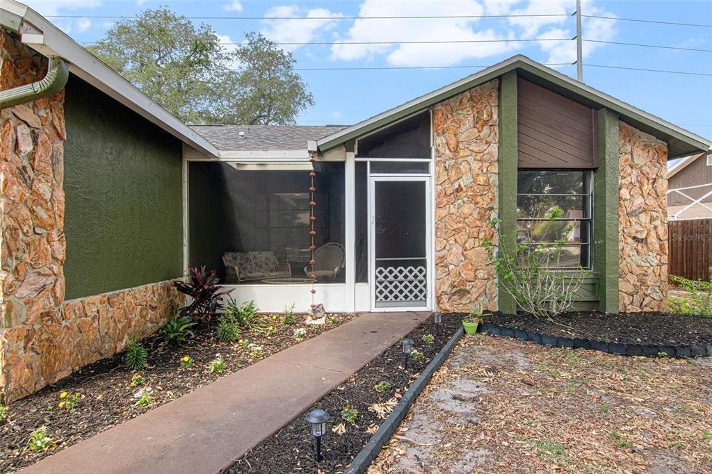 A single-story house features a stone facade, a screened-in porch, and a concrete walkway — 4105 SPRING WAY CIRCLE, VALRICO, FL