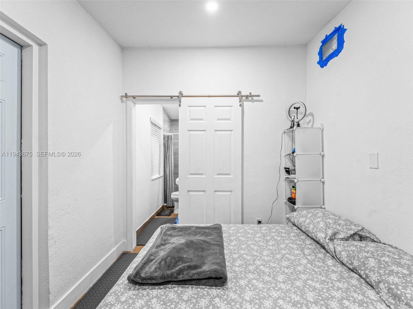 A bedroom features a sliding barn door leading to a bathroom and a bed — 11415 SW 56th St, Miami FL 33165, MIAMI, FL