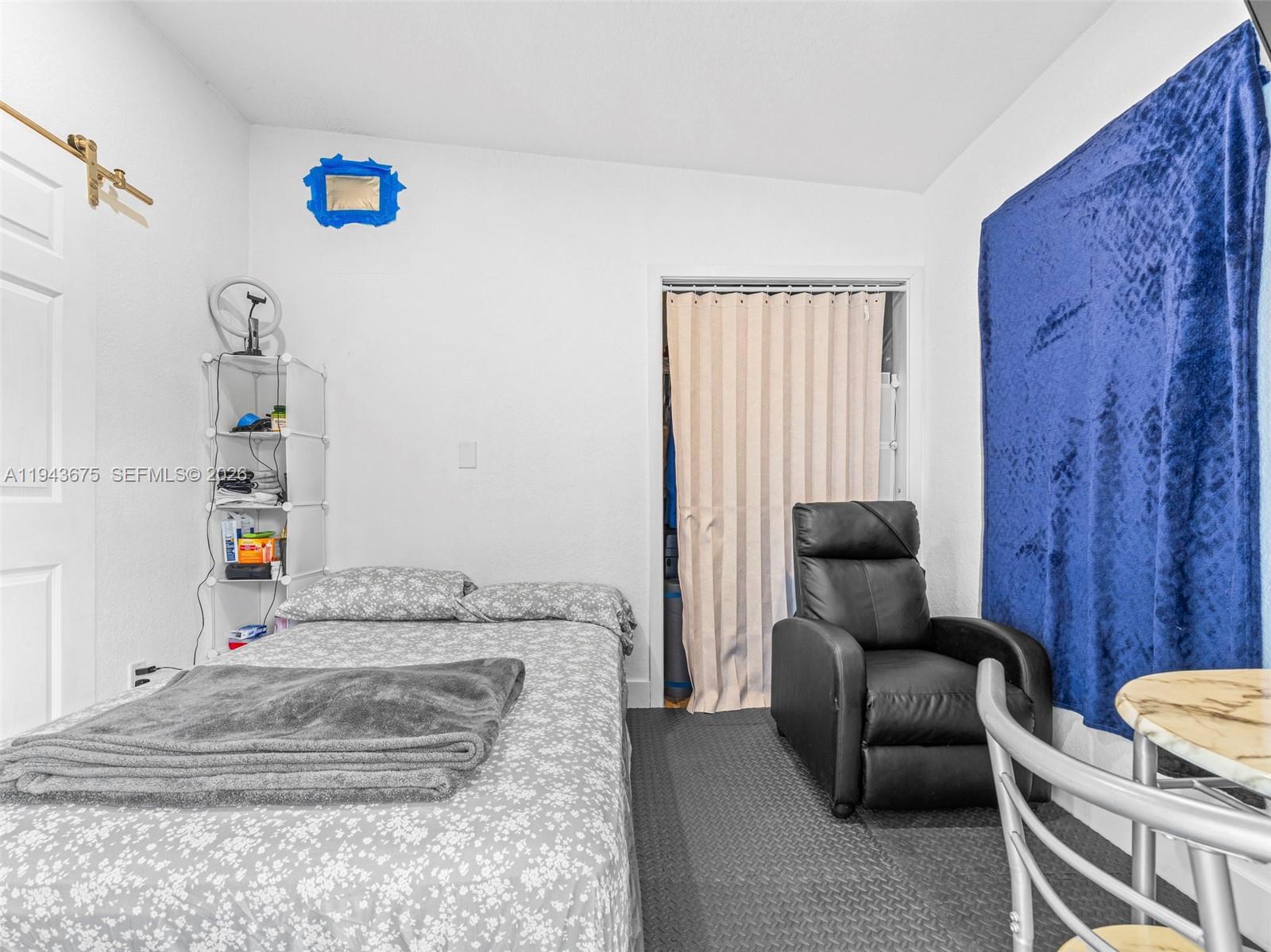 A bedroom features a bed, a black recliner, a closet with a curtain, and shelving — 11415 SW 56th St, Miami FL 33165, MIAMI, FL